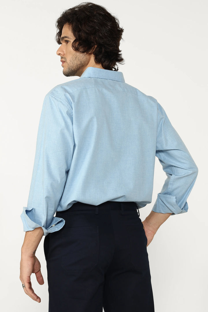 Man wearing a oxford blue shirt and dark pants on a white background
