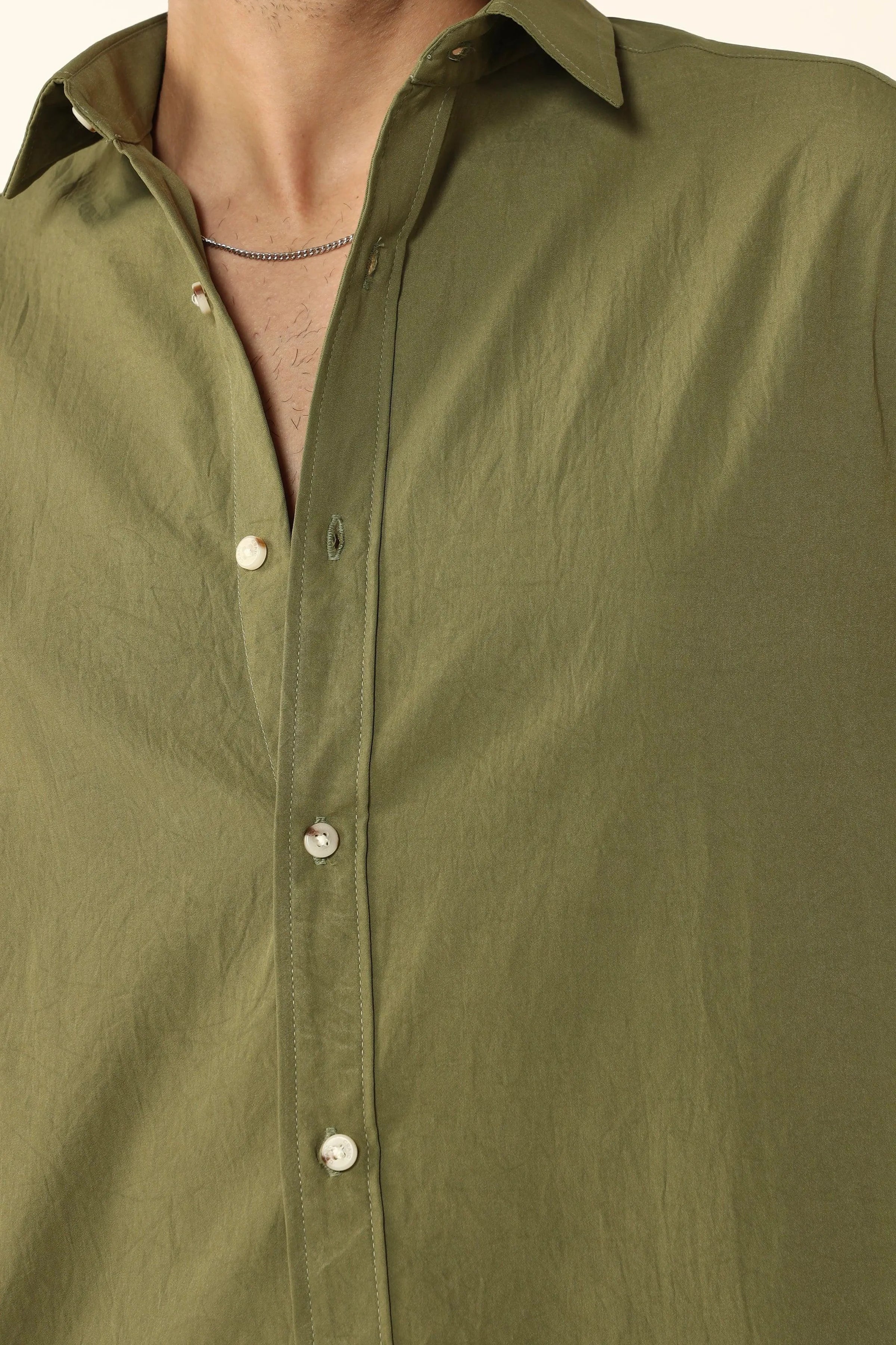 Close-up of a Olive Creased Cotton button-up shirt with a plain background