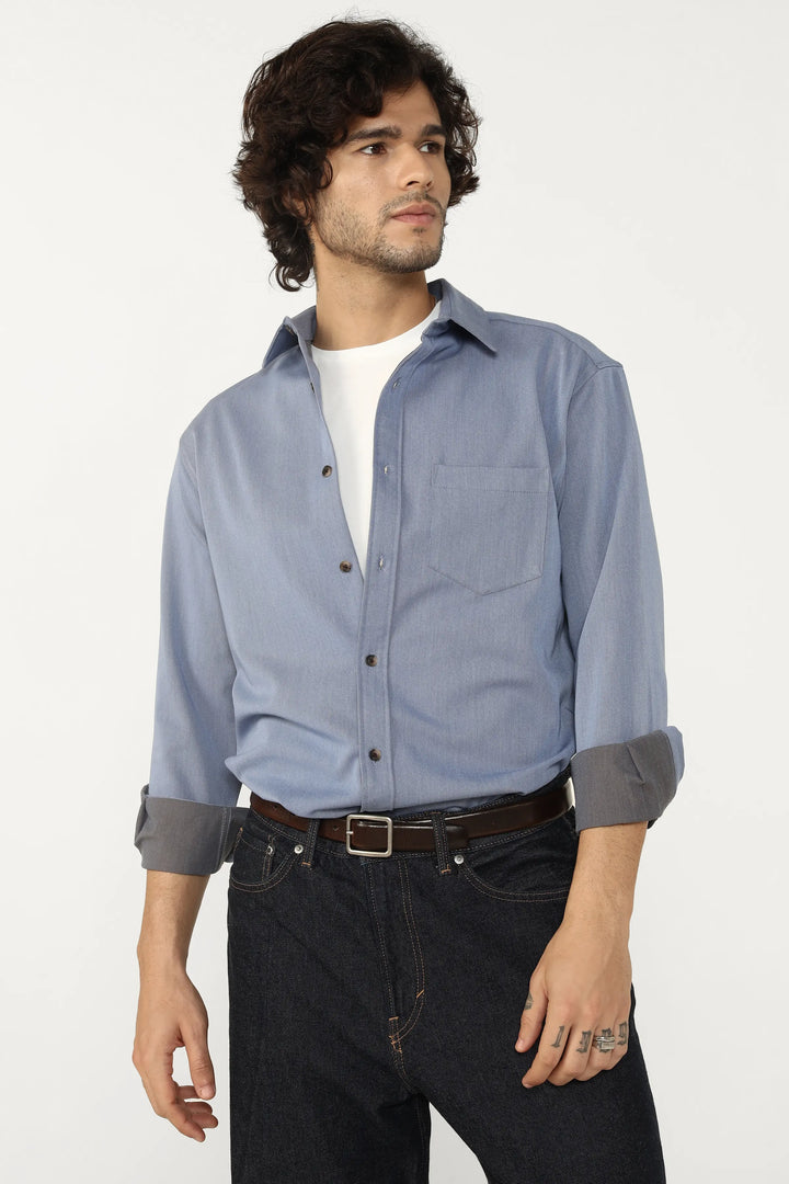 Man wearing a Oxford Cotton Twill button-up shirt and dark jeans on a white background