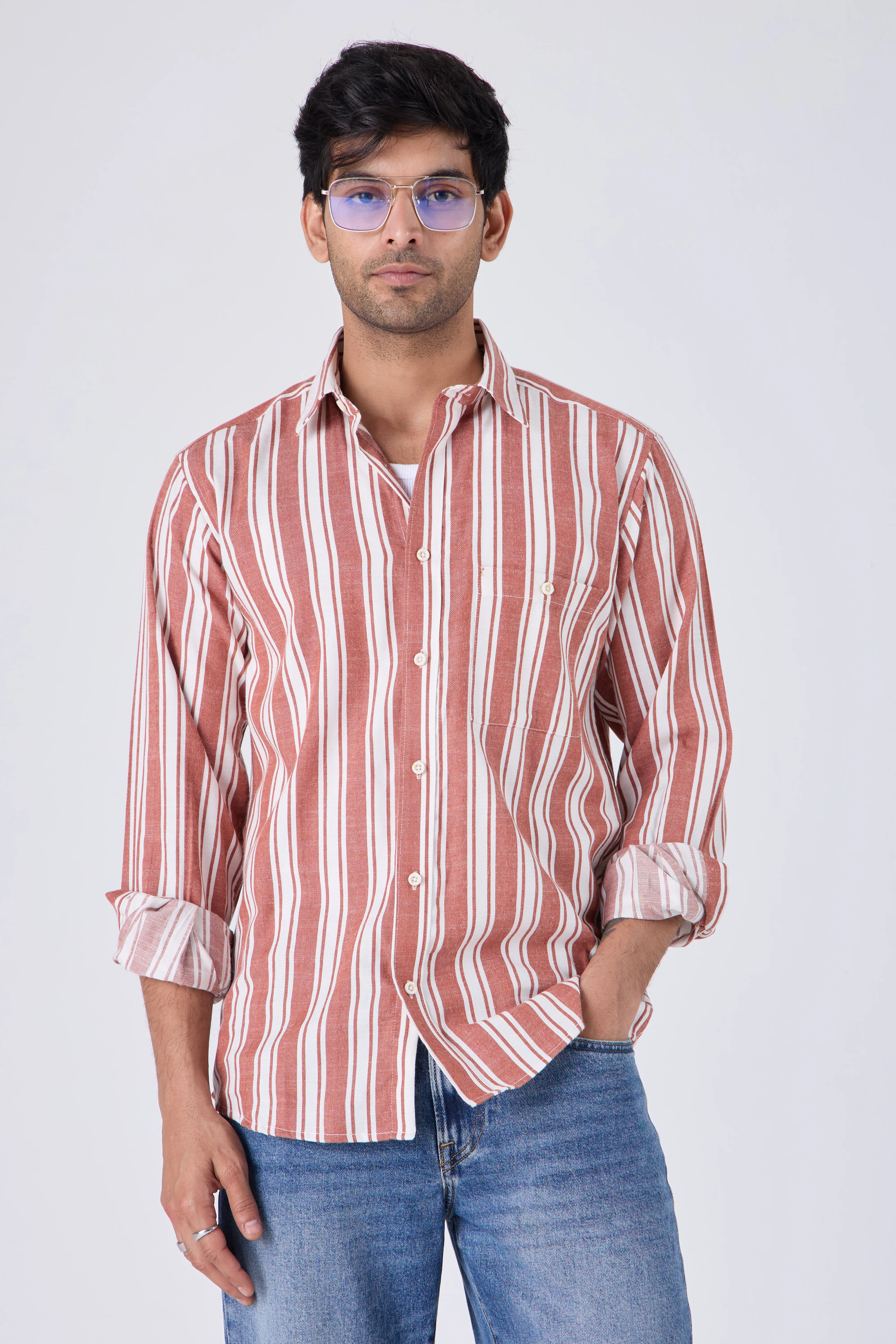Man wearing a tan cotton striped shirt with rolled-up sleeves against a plain background