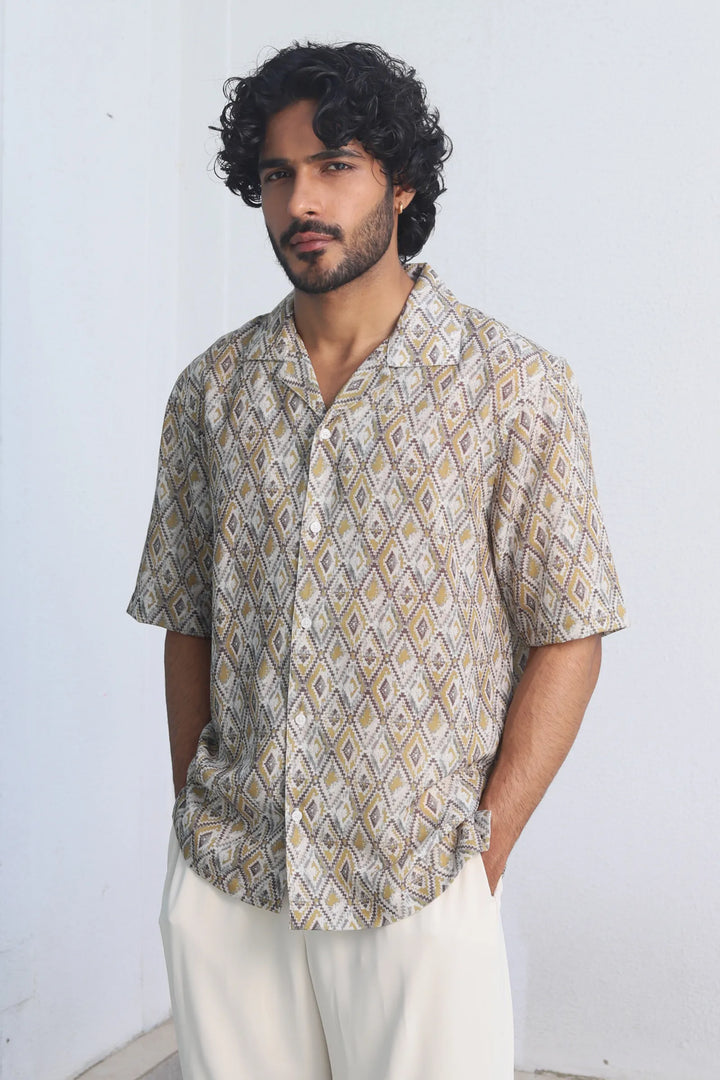 Man wearing a Yellow Harlequin Printed Shirt and white pants against a plain background