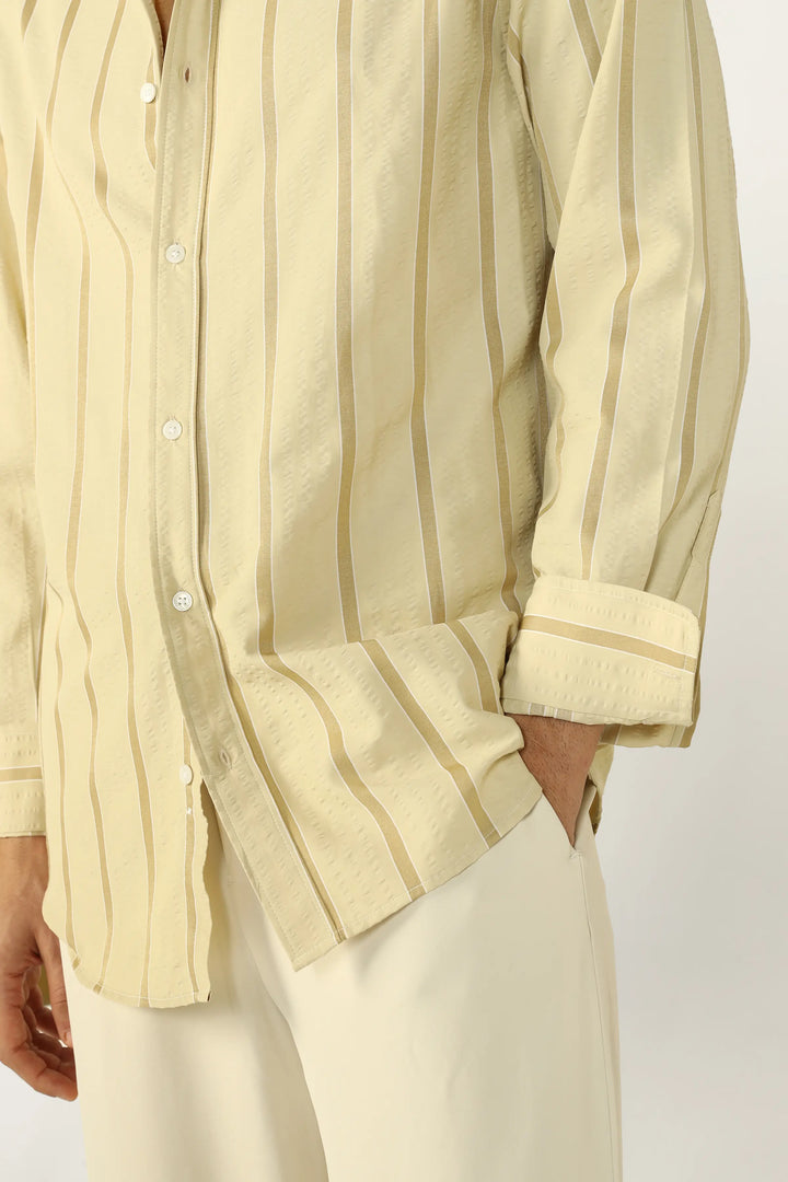 Person wearing a Yellow Seersucker striped shirt with rolled-up sleeves on a plain background