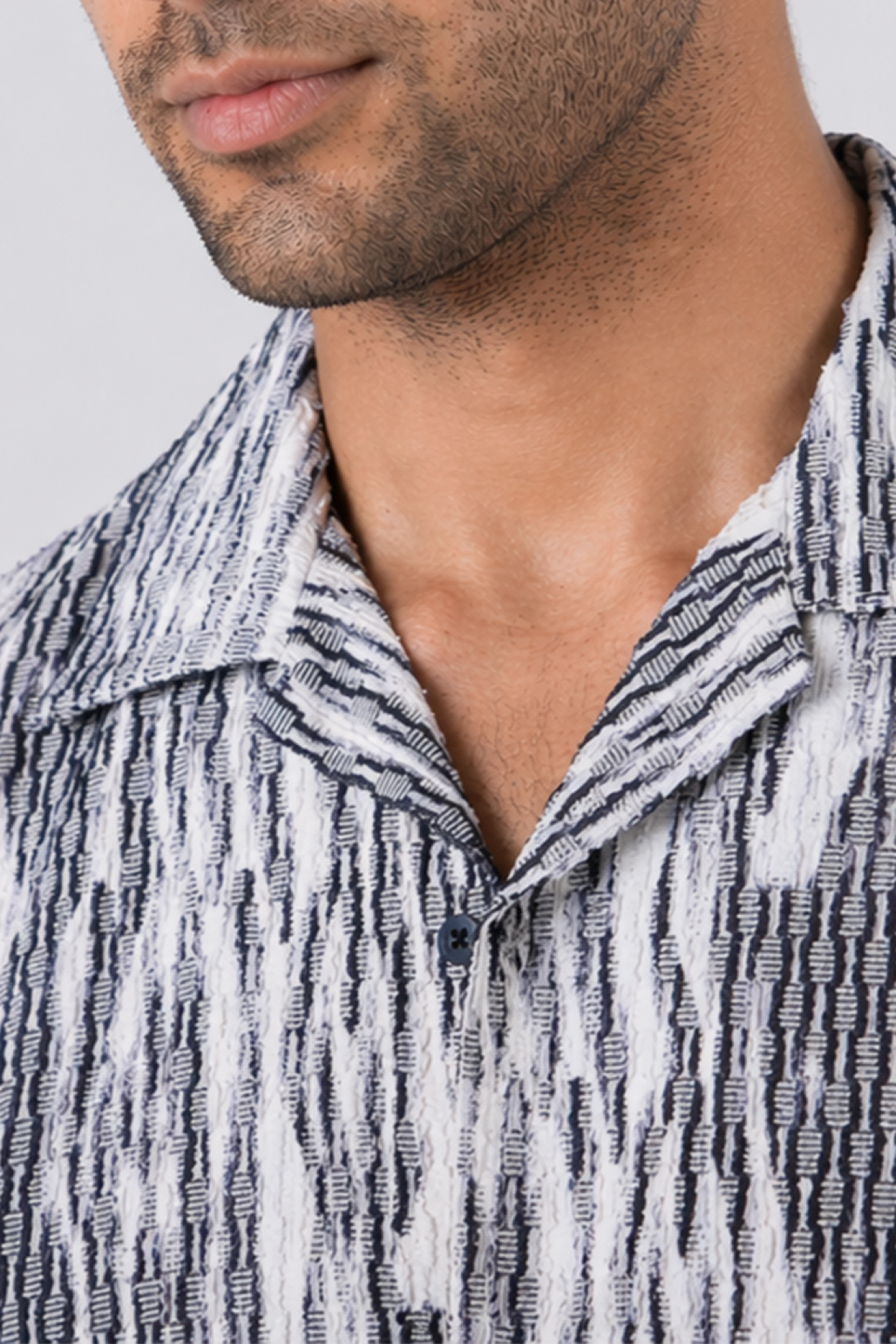 Close-up of a man wearing a patterned shirt with a neutral background