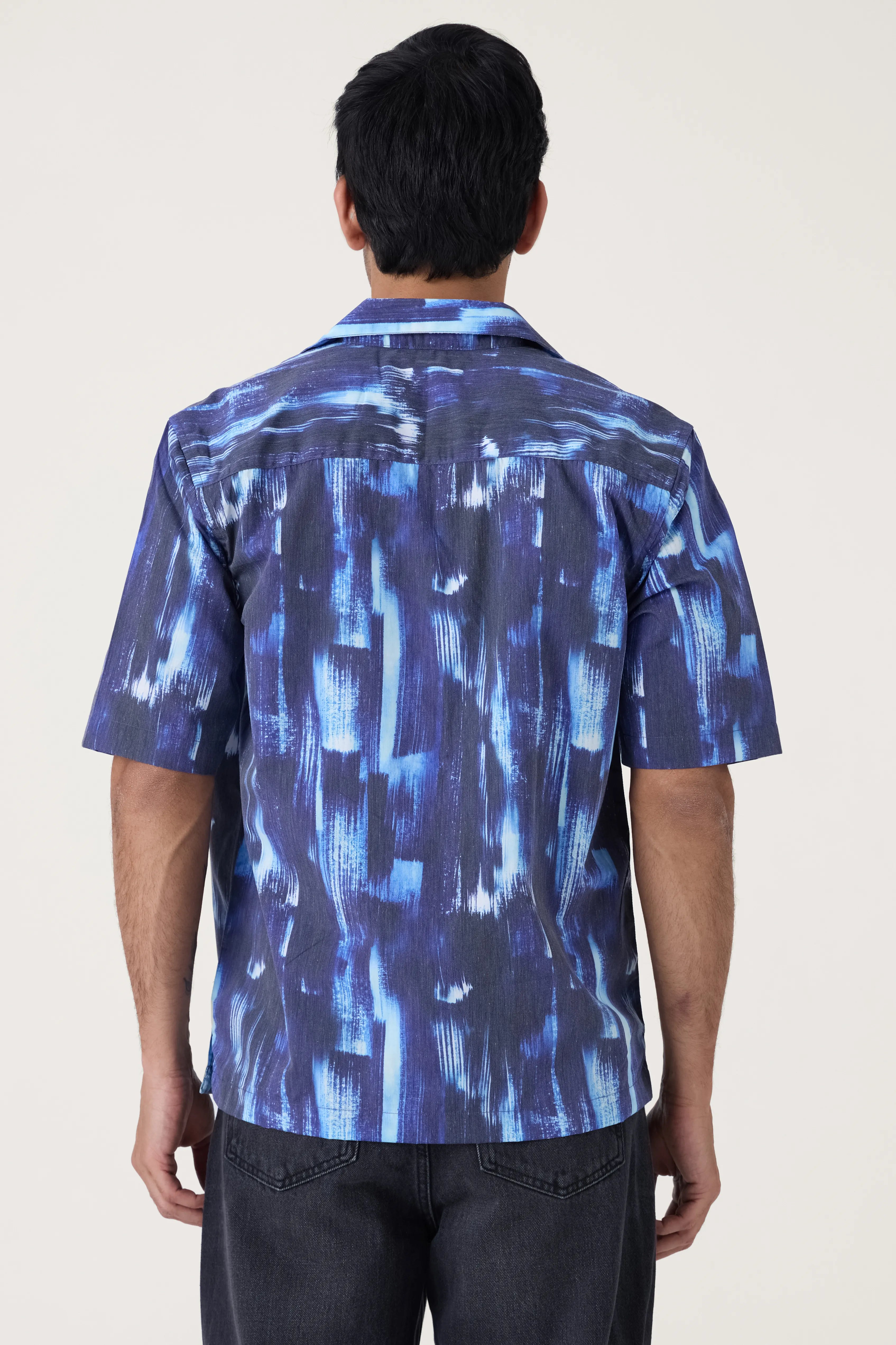 Person wearing a blue patterned shirt with a white background