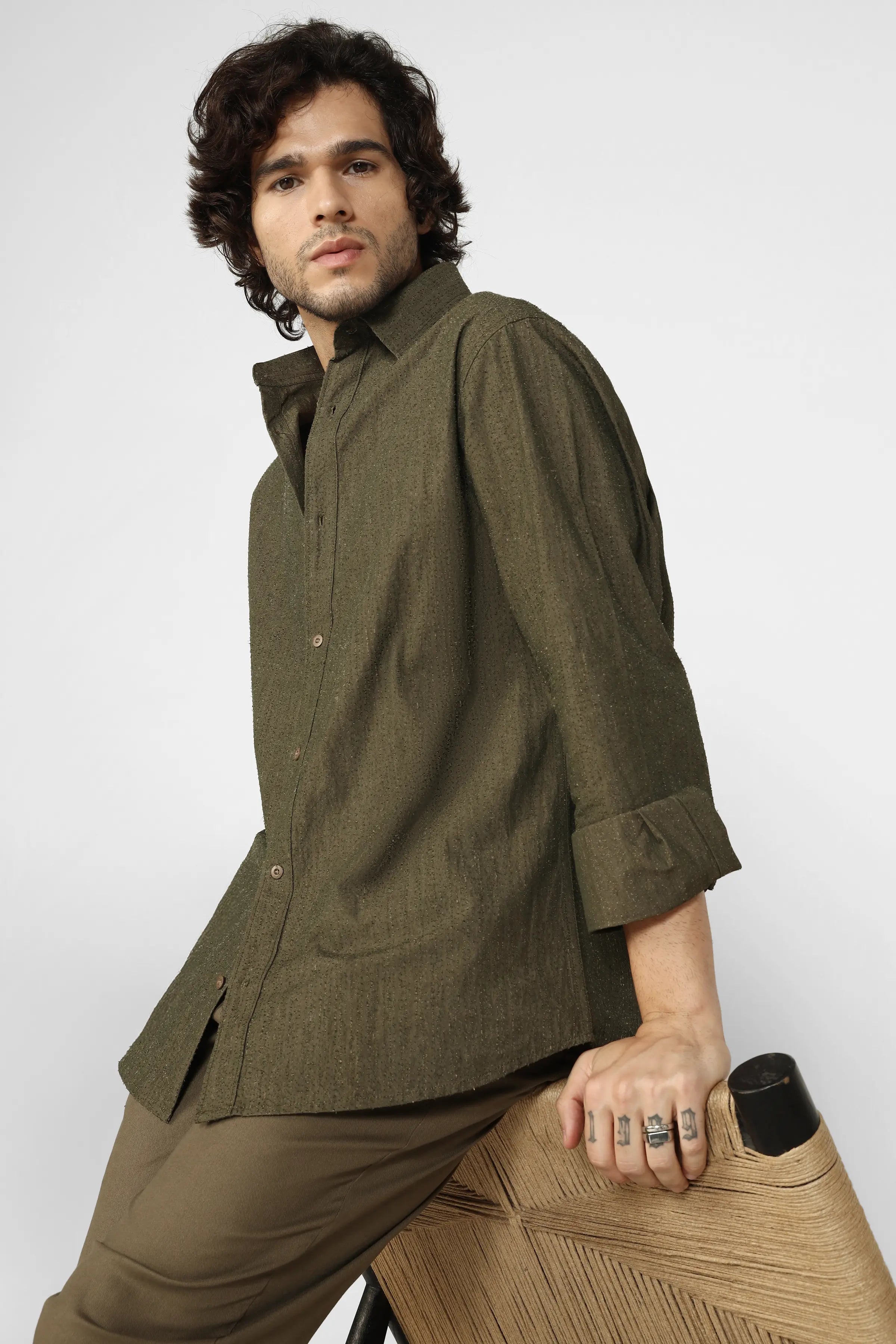 Man wearing a green shirt and brown pants against a white background