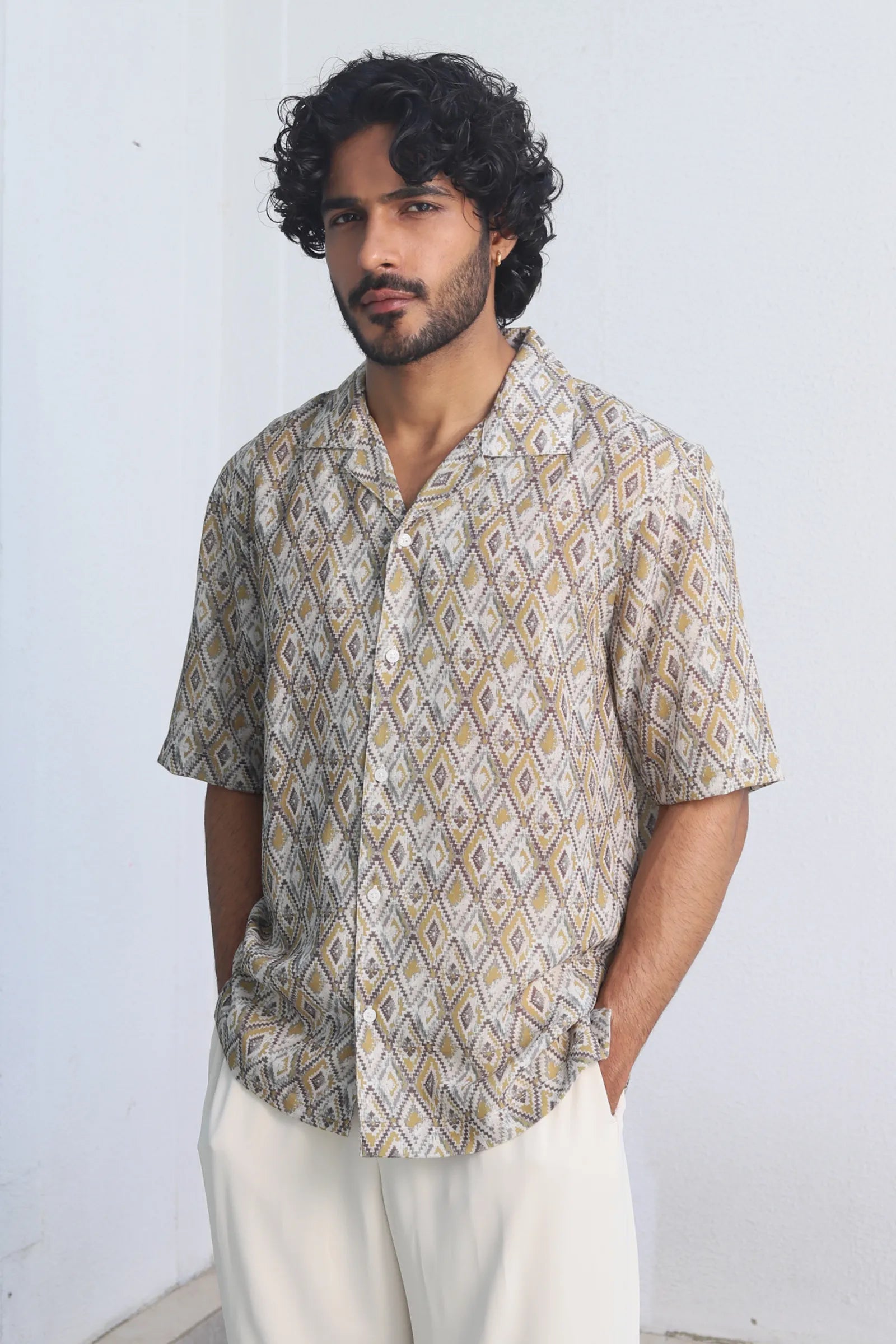 Man wearing a Yellow Harlequin Printed Shirt and white pants against a plain background
