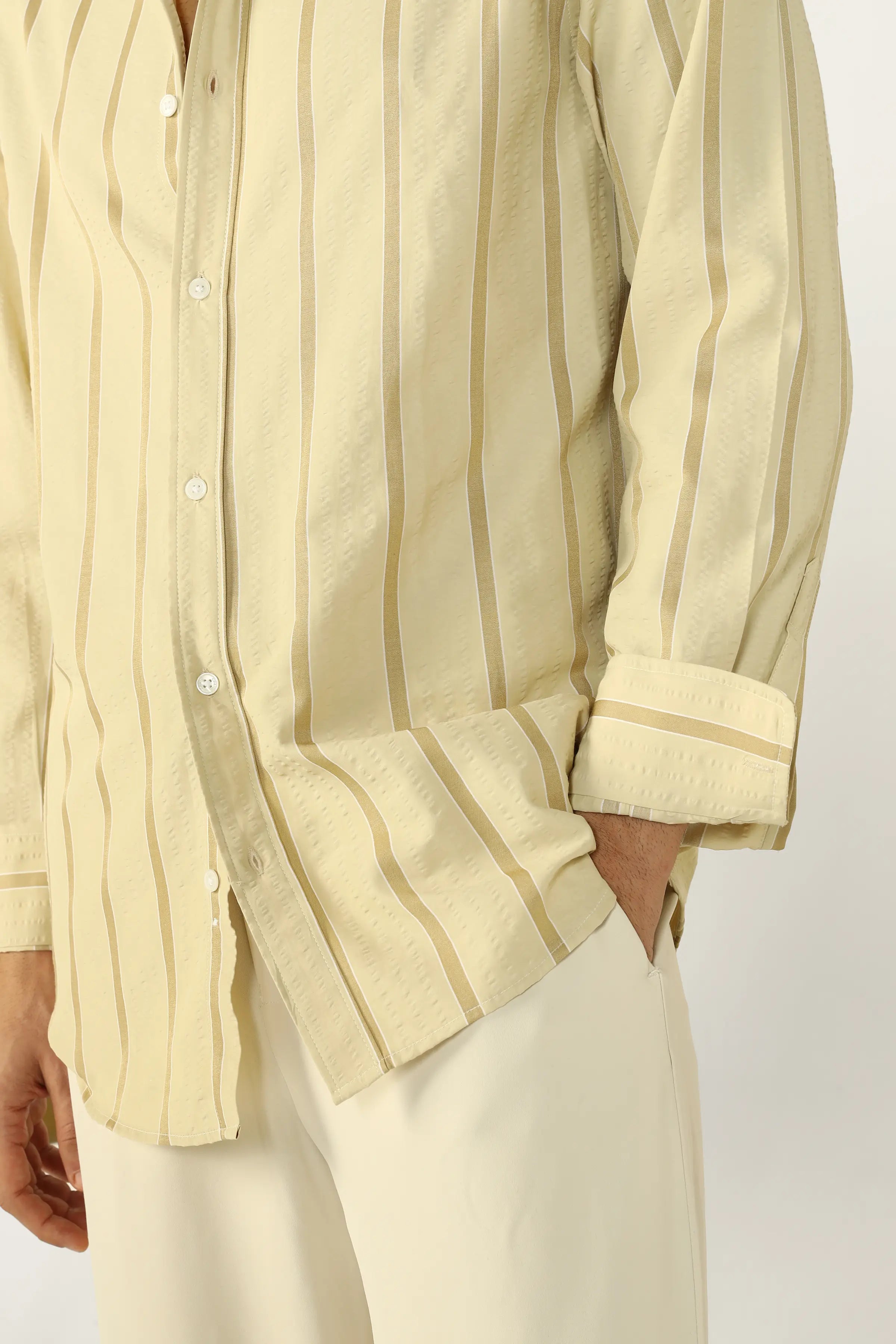 Person wearing a Yellow Seersucker striped shirt with rolled-up sleeves on a plain background
